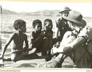 PAPUA, NEW GUINEA. 1942-07. THESE THREE SMALL PAPUAN BOYS COME IN FOR CLOSE SCRUTINY FROM THE AUSTRALIAN INFANTRYMAN ON THE RIGHT. THE SOLDIERS ARE MEMBERS OF A PATROL IN THE COASTAL SECTION AND ..
