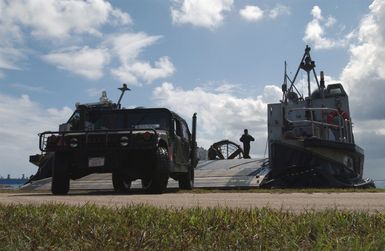 Deployed from a US Navy (USN) Landing Craft, Air Cushioned (LCAC), a US Marine Corps (USMC) High-Mobility Multipurpose Wheeled Vehicle (HMMWV) arrives at the beach in Inner Apra Harbor, Guam. Both are here taking part in Exercise TANDEM THRUST 2003