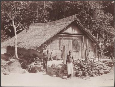 A man and two children outisde a Pago Pago house, Savo, Solomon Islands, 1906 / J.W. Beattie