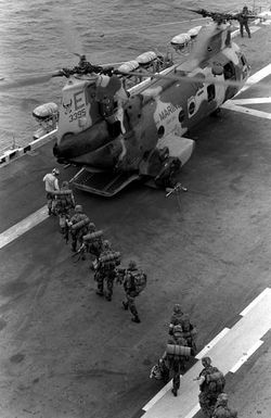 Marines of the 22nd Marine Expeditionary Unit (22nd MEU) are led to a Marine Medium Helicopter Squadron 261 (HMM-261) CH-46E Sea Knight helicopter aboard the amphibious assault ship USS SAIPAN (LHA 2) during a rehearsal for Operation Sharp Edge. The SAIPAN is on station off the coast of Liberia