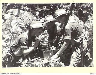 LAE, NEW GUINEA. 1945-03-11. SIGNALLERS OF THE NEW GUINEA SCHOOL OF SIGNALS REPAIRING A WS208 MARK II SET IN THE JUNGLE