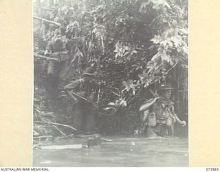 SARANG RIVER, NEW GUINEA. 1944-05-26. TROOPS OF THE 35TH INFANTRY BATTALION MOVE DOWN AN EMBANKMENT TO CROSS THE RIVER DURING THEIR DRIVE UP THE COAST TO WEWAK. IDENTIFIED PERSONNEL ARE:- PRIVATE ..