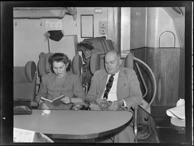 Interior view of aircraft, includes unidentified man and woman on Tasman Empire Airways air boat RMA New Zealand ZK-AME, flight to Fiji