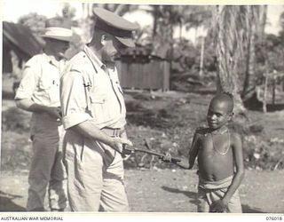 LAE, NEW GUINEA. 1944-09-18. TX2002 BRIGADIER J. FIELD, DSO, ED, COMMANDING, 7TH INFANTRY BRIGADE (2) PRESENTING AN AXE TO ONE OF THE FIVE NATIVE LADS WHO ESCORTED HIM AND VX48010 MAJOR J. ..