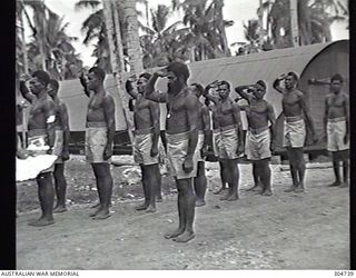 LUNGGA, GUADALCANAL, BRITISH SOLOMON ISLANDS PROTECTORATE. 1943-10-14. NATIVE POLICEMEN SERVING WITH THE COASTWATCHER ORGANISATION OF THE NAVAL INTELLIGENCE DIVISION, RAN, SALUTE AS THEY ARE ..