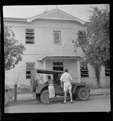 Two unidentified men waiting next to a jeep outside a post office in Port Moresby, Papua New Guinea