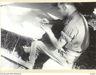 ALEXISHAFEN, NEW GUINEA. 1944-05-27. NX127899 DRIVER V.W. HILDER, IN A TENT COVERED POLLING BOOTH AT HEADQUARTERS 8TH INFANTRY BRIGADE RECORDING HIS VOTE IN THE NEW SOUTH WALES STATE ELECTIONS
