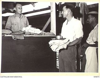 LAE AREA, NEW GUINEA. 1945-08-11. PRIVATE D. SHAW (2) BEING ISSUED WITH HOSPITAL KIT BY SERGEANT FALVEY (1) AT 2/7 GENERAL HOSPITAL