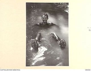 WONGINARA MISSION, NEW GUINEA. 1945-04-04. PRIVATE R.G. GREEN, 2/3 INFANTRY BATTALION, FLOPS FULLY CLOTHED INTO A CREEK AFTER RETURNING FROM FORWARD POSITIONS IN THE TORRICELLI MOUNTAINS, INLAND ..