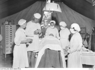 PORT MORESBY, PAPUA. C. 1942-10. AT THE MEDICAL RECEIVING STATION, A PATIENT FROM MILNE BAY IS TREATED ON THE OPERATING TABLE IN THE TENT BY RAAF DOCTOR, SISTER (LEFT) AND WAAAF ORDERLIES