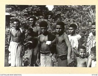 REMPI, NEW GUINEA. 1944-05-09. AN OFFICER FROM THE 35TH INFANTRY BATTALION (1), QUESTIONS NATIVES BESIDE THE ROAD TO ALEXISHAFEN. THE NATIVES HAVE EMERGED FROM THE JUNGLE IN RESPONSE TO A CALL MADE ..