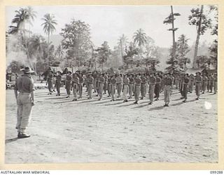 RABAUL, NEW BRITAIN, 1945-12-06. MEMBERS OF D COMPANY, 67 INFANTRY BATTALION, 34 BRIGADE GROUP, BRITISH COMMONWEALTH OCCUPATION FORCE (BCOF), AT RIFLE AND MARCHING DRILL, PRESENT ARMS UNDER THE ..
