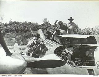 TOROKINA, BOUGAINVILLE ISLAND. 1944-12-23. WARRANT OFFICER J. REYNOLDS, NO.17 PHOTO SQUADRON 13TH UNITED STATES AIR FORCE EXPLAINING THE COCKPIT CONTROLS OF A P38 LOCKHEED "LIGHTNING" AIRCRAFT TO ..