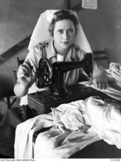 MADANG, NEW GUINEA. C. 1945. THE NURSES TAKE TURNS AT MENDING SHEETS, PYJAMAS, PILLOW SLIPS ETC AT NO. 1 MEDICAL RECEIVING STATION RAAF. 500440 SISTER M. RODDA OF MALDON, VIC, AT WORK ON THE ..