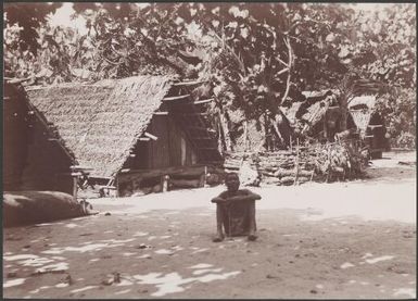 Ni-Vanuatu man sitting near buildings in the village of Nerinignam, Mota Lava, Banks Islands, 1906 / J.W. Beattie