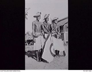 SAIDOR, NEW GUINEA. 1945-09-03. THREE SMILING NATIVES DRESSED IN RAAF SLOUCH HATS HOLD A RAAF ENSIGN DURING CELEBRATIONS TO MARK THE SIGNING BY THE JAPANESE OF THE SURRENDER DOCUMENT AT MANILA THE ..