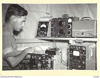 LAE, NEW GUINEA. 1945-03-11. A SIGNALLER CHECKING TEST EQUIPMENT AT HEADQUARTERS, 19TH LINES OF COMMUNICATION SIGNALS. EQUIPMENT IS LEFT TO RIGHT:- BELOW: RECEPTION SET NO.4; VALVE AND CONDENSER ..