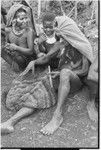 Pig festival, singsing, Kwiop: woman with marsupial furs and shell valuables weaves a netbag