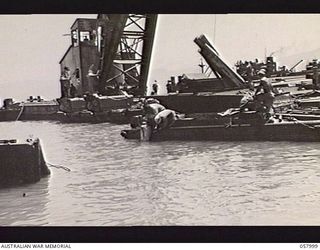 LAE, NEW GUINEA. 1943-10-12. A DIVER OF THE UNITED STATES SMALL SHIPS SECTION GOING BELOW TO SALVAGE A SUNKEN JAPANESE BARGE