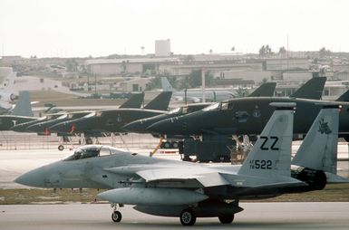 An 18th Tactical Fighter Wing F-15C Eagle aircraft taxis past a row of 28th Bombardment Wing B-1B aircraft during exercise Giant Warrior '89