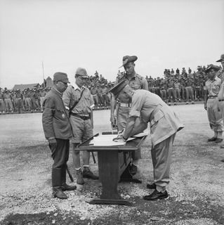 CAPE WOM, NEW GUINEA, 1945-09-13. MAJOR-GENERAL H.C.H. ROBERTSON, GENERAL OFFICER COMMANDING 6 DIVISION, SIGNING THE INSTRUMENT OF SURRENDER. LIEUTENANT-GENERAL H. ADACHI, COMMANDER 18 JAPANESE ..