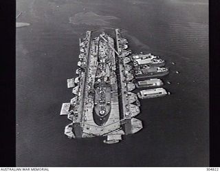 PACIFIC OCEAN. C.1945. AN AERIAL VIEW OF AN ADVANCED BASE SECTIONAL DOCK OF THE US NAVY AT A PACIFIC ISLAND BASE. THE DOCK IS SERVICING TWO LIBERTY SHIPS. NOTE THE BARGES ALONGSIDE TO PROVIDE ..