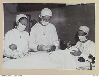 BOUGAINVILLE, 1945-04-19. SISTER N.H. HOLLOWAY, AUSTRALIAN ARMY NURSING SERVICE (1), WORKING IN THE OPERATING THEATRE, 2/1 GENERAL HOSPITAL ASSISTED BY MEDICAL ORDERLIES