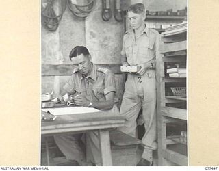 LAE BASE AREA, NEW GUINEA. 1944-12-04. VX112084 CAPTAIN A.L. KONG, OFFICER- IN- CHARGE (1) CHECKING SPARE PARTS IN THE STORE OF THE 2/77TH LIGHT AID DETACHMENT. IDENTIFIED PERSONNEL IS:- VX125235 ..