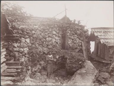 A man standing in front of a fort in the village of Qarea, Malaita, Solomon Islands, 1906 / J.W. Beattie