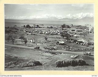 LAE, NEW GUINEA, 1944-03-27. ONE OF A SERIES OF PHOTOGRAPHS VIEWING THE WHARVES, SHIPPING, NEW ROADS, BUILDINGS AND THE AIRSTRIP WITH SALAMAUA POINT IN THE BACKGROUND. (JOINS WITH PHOTOGRAPHS ..