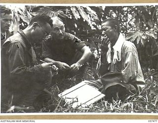 NADZAB, NEW GUINEA. 1943-09-20. UNITED STATES ARMY INTERPRETER, SERGEANT MUNEKAWA (FOREGROUND) INTERROGATING A CHINESE COOLIE, WHO HAD BEEN EMPLOYED BY THE JAPANESE, WHILE SERGEANT D.J. GRIMLEY ..