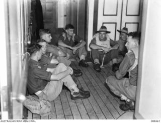 AT SEA. 1945-04-04. OFFICERS OF 26 INFANTRY BRIGADE SIT TING IN THE CORRIDOR OUTSIDE THEIR CABINS AT THEIR AIR RAID ALERT POSTS ABOARD THE DUTCH TROOPSHIP MV VAN HEUT SZ WHILE THE VESSEL IS SAILING ..