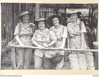 BRISBANE, QLD. 1945-02-21. MEMBERS OF THE AUSTRALIAN ARMY MEDICAL WOMEN'S SERVICE, THEY AWAIT EMBARKATION FROM FRAZER'S PADDOCK TO THE 2/1 GENERAL HOSPITAL AT BOUGAINVILLE. IDENTIFIED PERSONNEL ..