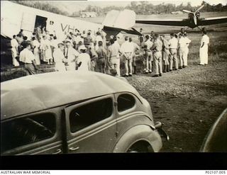 Salamaua, New Guinea. 1941-12. A crowd stands on the airfield watching women and children board the tri-motor Junkers 31 aircraft VH-UOV owned by Bulol Gold Dredging Ltd. This aircraft evacuated ..