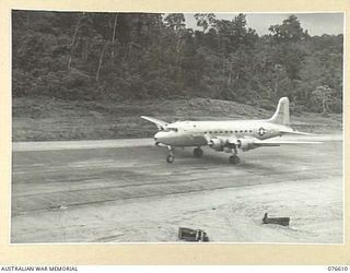 FINSCHHAFEN AND MARKHAM VALLEY, NEW GUINEA. 1944-10-19. ONE OF THE HUGE UNITED STATES ARMY AIR CORPS C54 DOUGLAS TRANSPORT AIRCRAFT TOUCHING DOWN ON THE AIRSTRIP UPON ITS ARRIVAL FROM THE UNITED ..