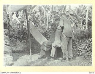 MILNE BAY, NEW GUINEA. 1943-01. THE UNIT BARBER AT WORK IN THE LINES OF THE 101ST ANTI TANK REGIMENT, ROYAL AUSTRALIAN ARTILLERY