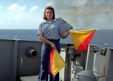 On board the submarine tender USS HOLLAND (AS-32), Signalman SEAMAN Apprentice (SNSA) Carey Gross demonstrates several flag signals used to communicate with other ships. The HOLLAND has just departed Apra Harbor, Guam for 45 days at sea