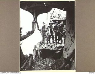 1943-09-24. NEW GUINEA. FALL OF LAE. SOLDIERS LOOK INSIDE THE WRECKED JAPANESE SHIP MYOKO MARU AGROUND ON A BEACH NEAR LAE