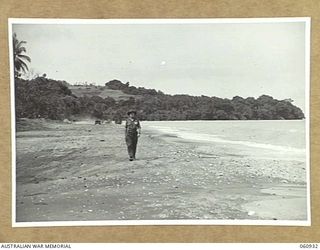 NEW GUINEA. 1943-11-28. MR SOUTHWELL-KIELY, WAR CORRESPONDENT, SYDNEY MORNING HERALD WALKING ALONG SCARLETT BEACH IN THE HEADQUARTERS, 24TH AUSTRALIAN INFANTRY BRIGADE AREA