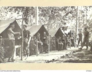 SIAR, NEW GUINEA. 1944-06-25. TROOPS WAITING FOR THE MESS PARADE IN THE TENT LINES OF C COMPANY, HEADQUARTERS, 57/60TH INFANTRY BATTALION. IDENTIFIED PERSONNEL ARE:- NX143569 PRIVATE N. RAMSAY (1); ..