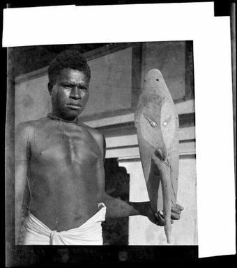 Man holding a mask from the Sepik river area, New Guinea, ca. 1936 / Sarah Chinnery