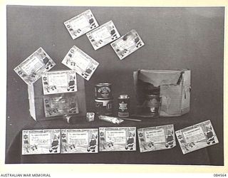 LAE AREA, NEW GUINEA. 1944-12-22. PILLAGED AUSTRALIAN COMFORTS FUND PARCELS SHOWING CONTAINERS AND CARDS CARRYING THE ADDRESSES OF DONORS