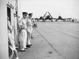 AT SEA OFF RABAUL, NEW BRITAIN. 1945-09-06. WING COMMANDER MATHISON AND GROUP CAPTAIN ROBERTS, ROYAL NEW ZEALAND AIR FORCE OFFICERS ON BOARD THE AIRCRAFT CARRIER HMS GLORY, WAITING FOR THE ARRIVAL ..