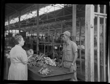 Market scene with woman at stall talking to vendor, Papeete, Tahiti