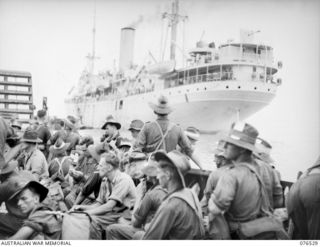 MILFORD HAVEN, LAE, NEW GUINEA. 1944-10-06. AN AUSTRALIAN LANDING BARGE LOADED WITH MEMBERS OF THE 36TH INFANTRY BATTALION APPROACHING THE DUTCH TROOPSHIP, "SWARTENHONDT" FOR THE UNIT'S MOVE TO NEW ..