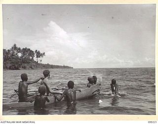 RABAUL, NEW BRITAIN, 1945-11-29. AN AUSTRALIAN SOLDIER OF 11 DIVISION WITH NATIVE BOYS OUT IN THE BAY IN A NATIVE CANOE