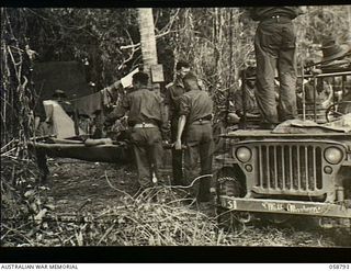 DUMPU, NEW GUINEA, 1943-10-10. WOUNDED ON A STRETCHER ARRIVING AT HEADQUARTERS, 21ST AUSTRALIAN INFANTRY BRIGADE, ON A CONVERTED JEEP
