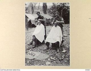 YAMIL 2, NEW GUINEA, 1945-08-01. PTE A.S. PETERSON (3) AND PTE L.K. REYNOLDS (4), BATTALION BARBERS, 2/6 INFANTRY BATTALION, CUTTING HAIR. IDENTIFIED PERSONNEL ARE:- PTE J. TURTON (1); PTE W.C. ..