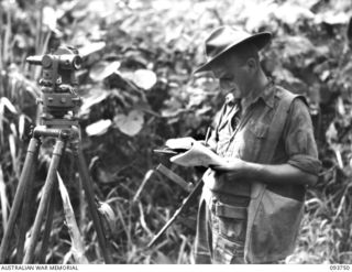 WEWAK AREA, NEW GUINEA, 1945-07-03. LANCE-BOMBARDIER A. BEASLEY, 2/6 SURVEY BATTERY, ROYAL AUSTRALIAN ARTILLERY, USING PENCIL AND LOG BOOK TO KEEP UP WITH THE COMPUTING. EACH AUSTRALIAN DIVISION IS ..