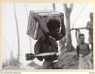 BERRY'S HILL, CENTRAL BOUGAINVILLE, 1945-06-27. A NATIVE CARRIER CARRYING A CASE OF APPLIES AND A 4.2 INCH MORTAR BOMB DURING THE MOVEMENT OF SUPPLIES FORWARD TO 7 INFANTRY BATTALION, ALONG THE ..